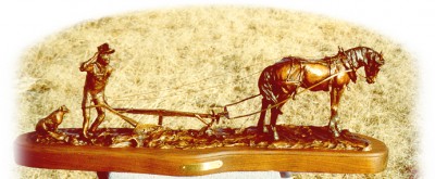 Bronze sculpture of farmer and horse plowing virgin soil.