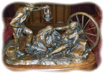 Bronze sculpture of midwife delivering a pioneer woman's baby.
