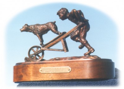 Bronze sculpture of boy and his dog playing.