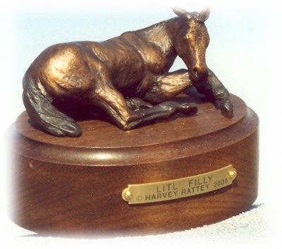 Bronze sculpture of a young filly laying down.
