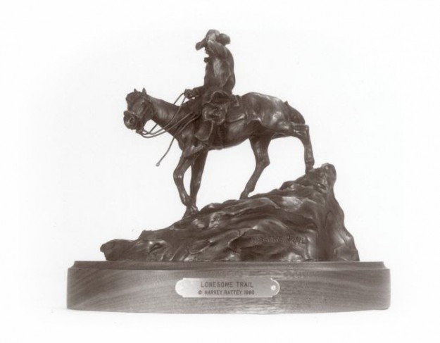 Bronze sculpture of a cowboy riding his horse down a steep trail.