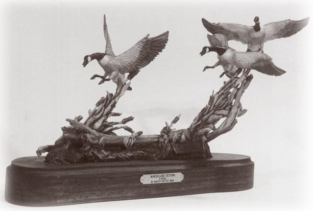 Bronze sculpture of  three Canada geese landing in cattails.