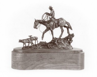 Bronze sculpture of a cowboy chasing calves.
