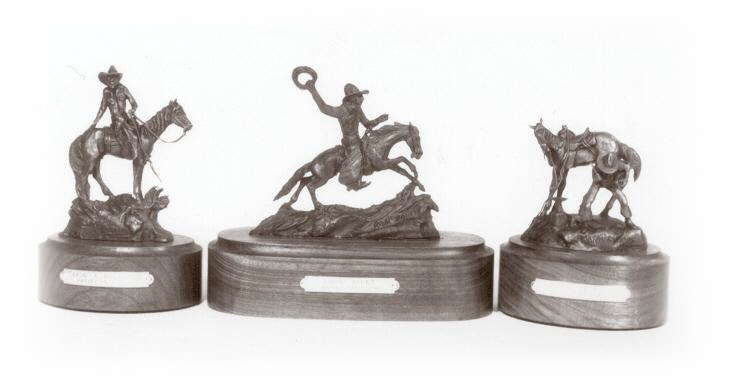 Three bronze sculptures of cowboys.