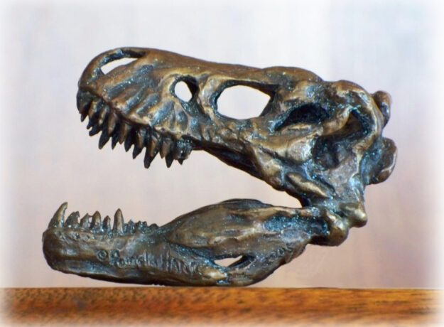 Miniature bronze sculpture of a T-Rex skull.