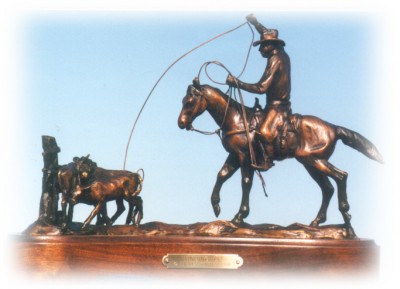 Bronze sculpture of cowboy on a horse roping a calf.