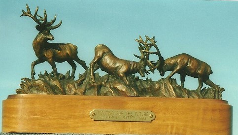 Bronze sculpture of two bull elk fighting while a third bull walks away.