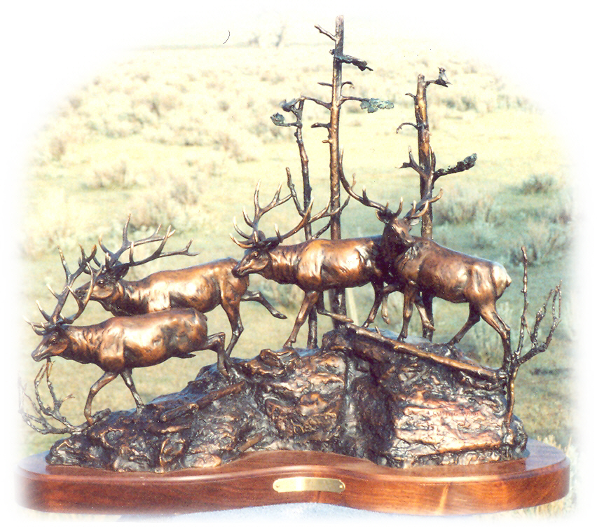 Bronze sculpture of four elk going up over a hilltop with trees in the background.