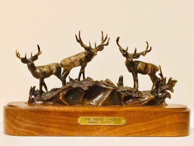 Bronze sculpture of three large mule deer bucks, each sporting a set of trophy antlers.