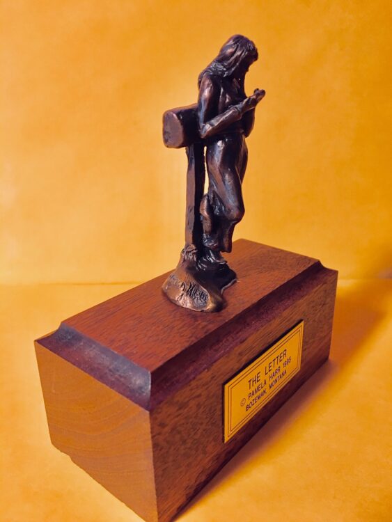 bronze sculpture of a young woman in summer clothes reading a letter.