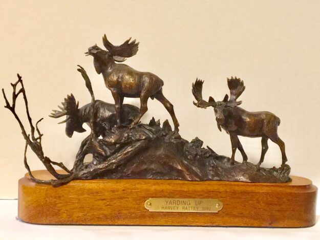 Bronze sculpture: Three bull moose gather on a hilltop.