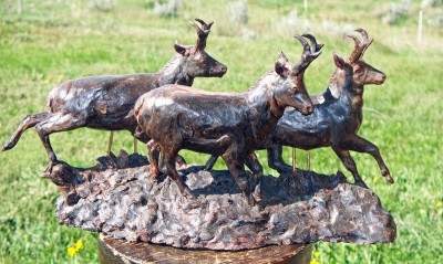 Bronze sculpture of three antelope running.