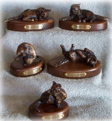 Five different bronze sculptures of tabby cats.