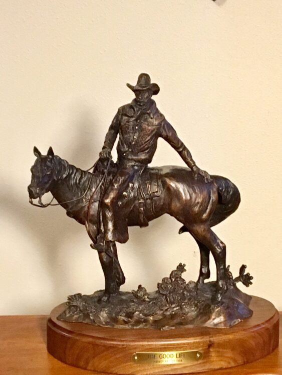 Bronze sculpture of a cowboy on his horse, facing the viewer.