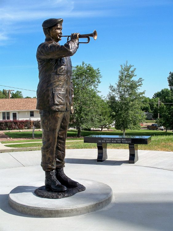 Life sized bronze sculpture by Pamela Harr of an Army bugler playing Taps.