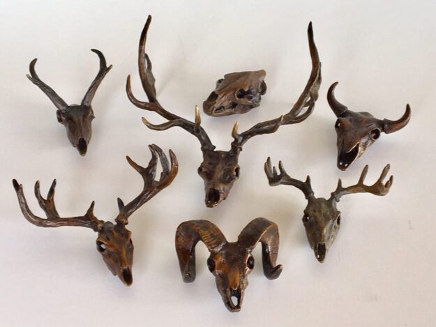 Collection of seven miniature bronze sculptures of wildlife skulls:  Pronghorn, elk, grizzly bear, bison, whitetail deer, bighorn sheep and mule deer.