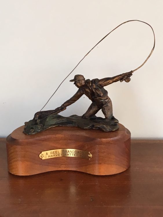 Bronze sculpture of a man fly fishing.