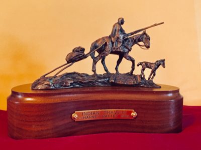 Bronze sculpture of a Native American riding a horse that is pulling a travois and has a foal