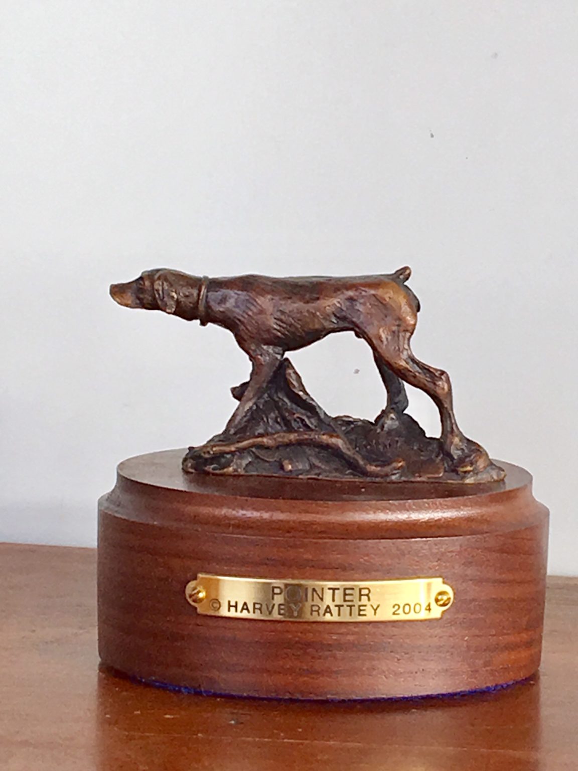 Bronze sculpture of hunting dog pointing at game.