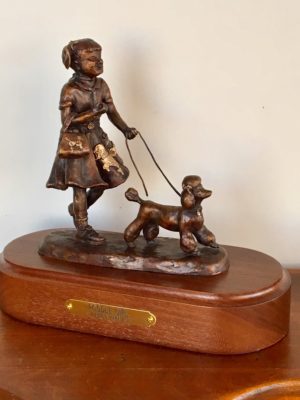 Bronze sculpture of a girl walking her poodle