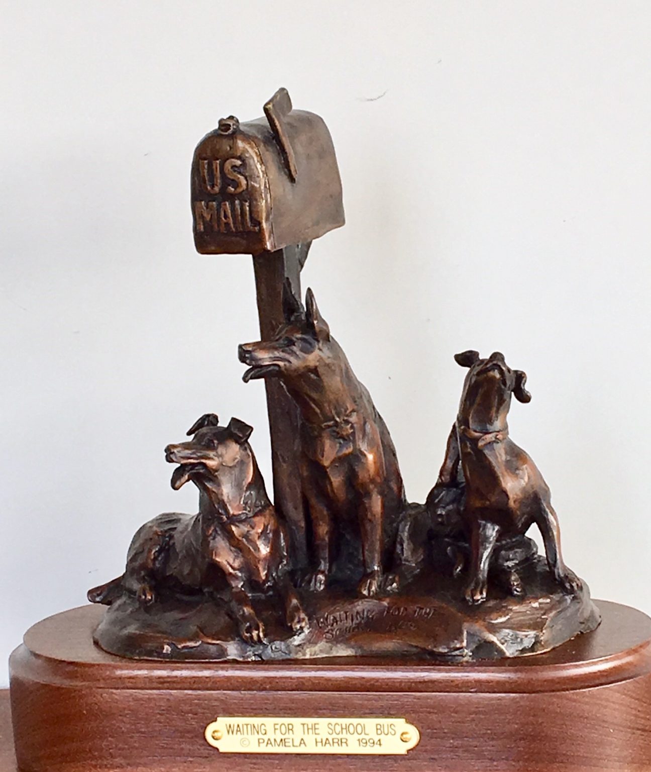 Bronze of 3 dogs waiting by a rural mailbox.