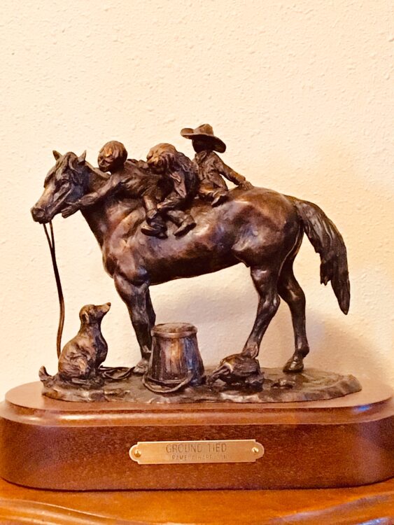 Bronze sculpture of three children riding a horse bareback