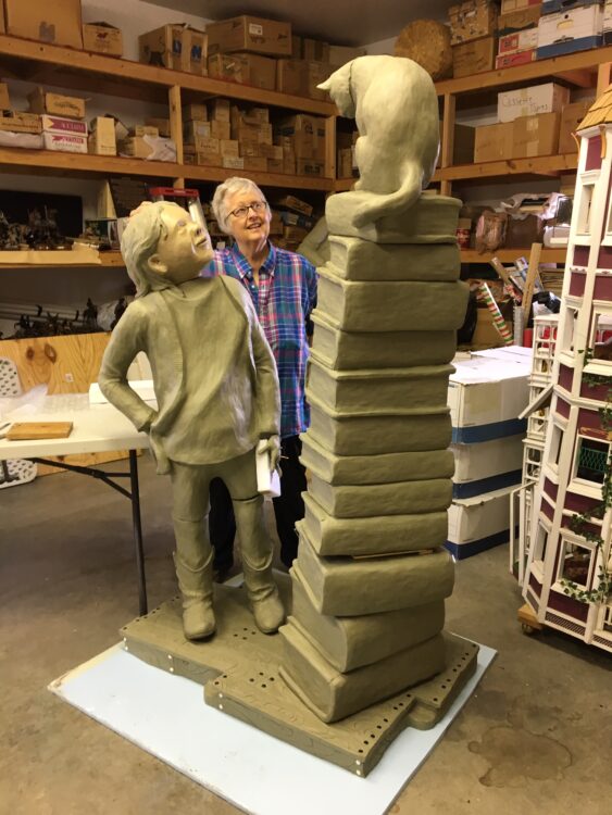 Artist Pamela Harr poses beside the clay model that will become the life-size bronze sculpture entitled Library Cat.