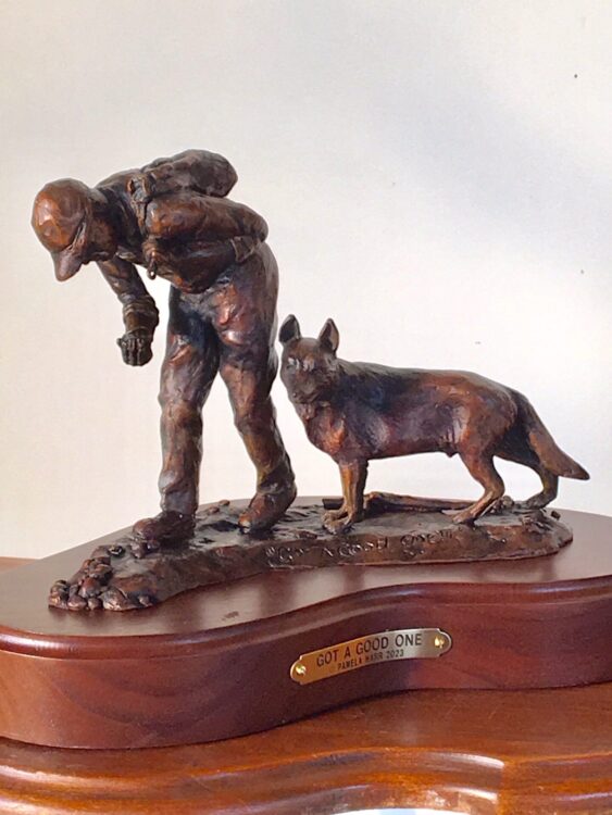 Bronze sculpture of a little boy and his dog hunting for agates.