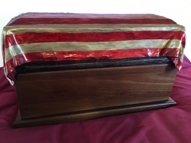 View of sculpture of the flag-draped casket of a military service person.