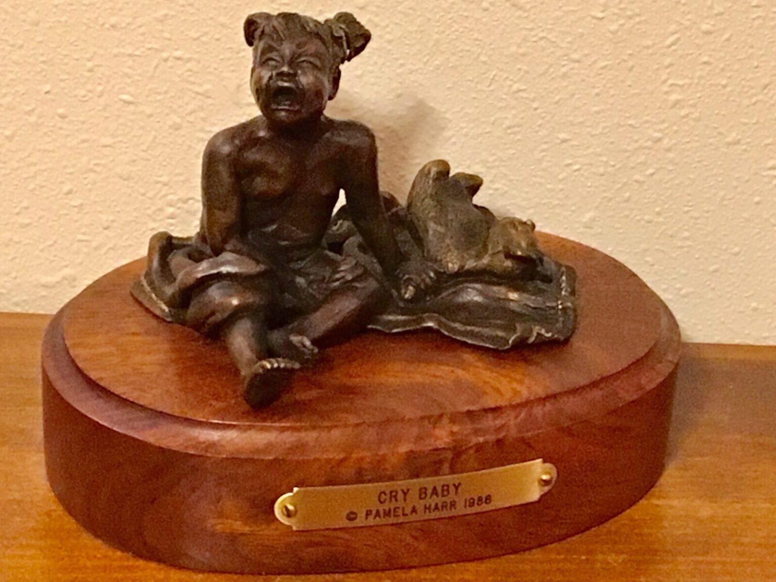 Bronze sculpture of a little girl crying.