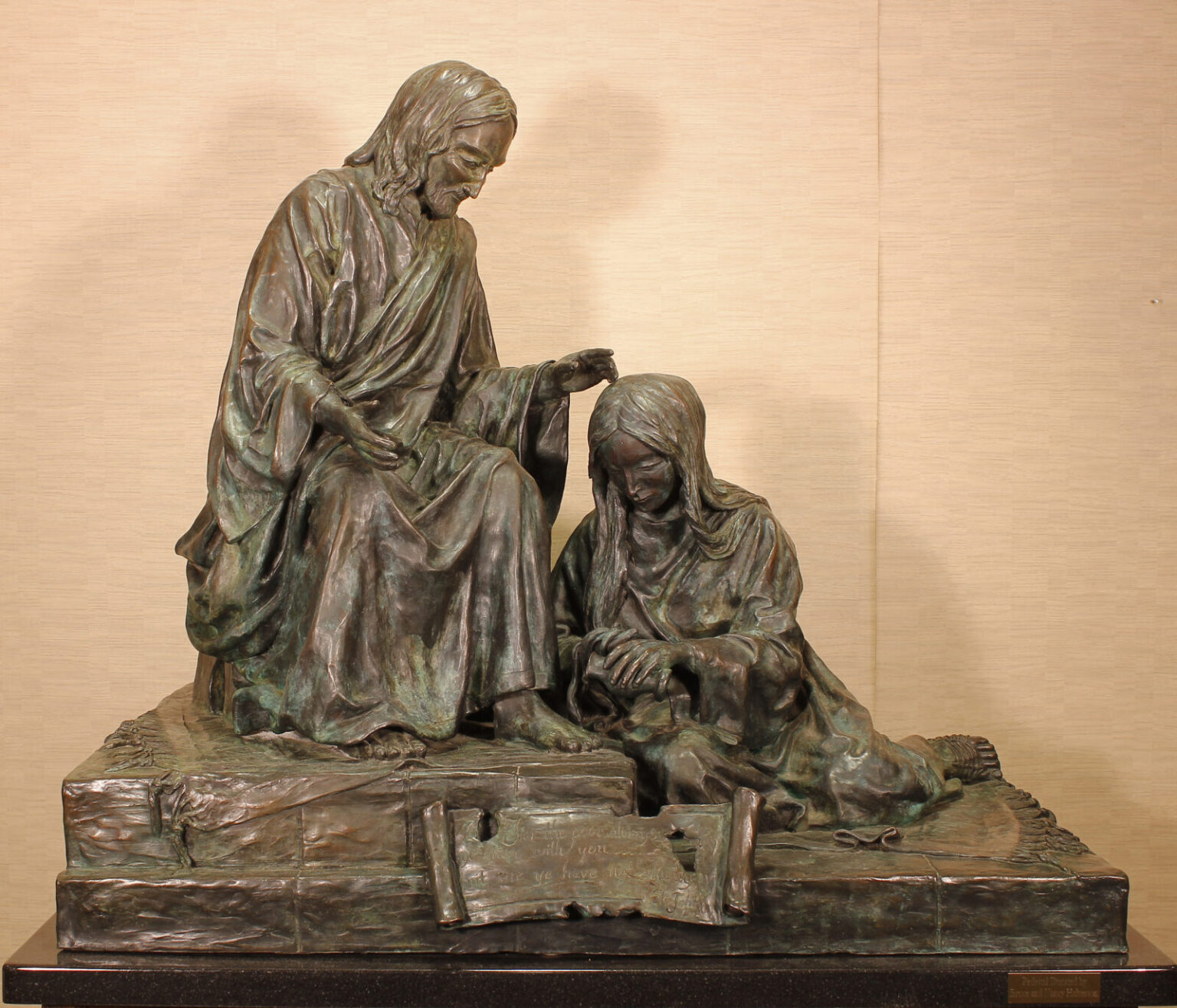 Bronze sculpture of Mary washing Jesus' feet.