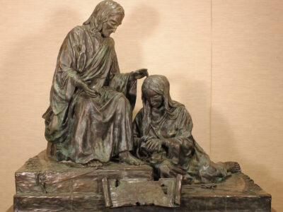 Bronze sculpture of Mary washing Jesus' feet.