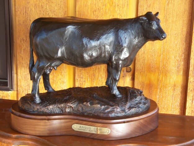 Bronze sculpture of a mature Angus beef cow on a black walnut base with bronze plaque.