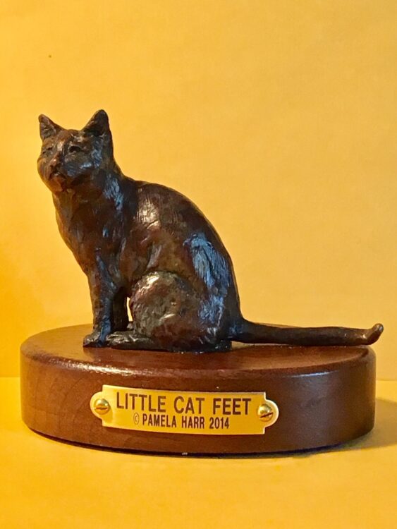 Bronze sculpture of a domestic cat sitting.