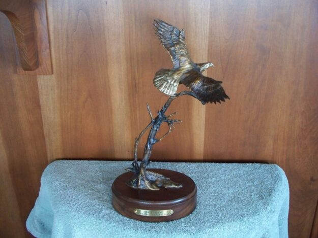 Bronze sculpture of a bald eagle taking flight.