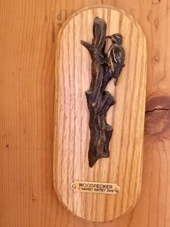 Small bronze sculpture of a woodpecker on a tree