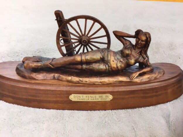 Bronze sculpture of a young woman lying next to a fence.