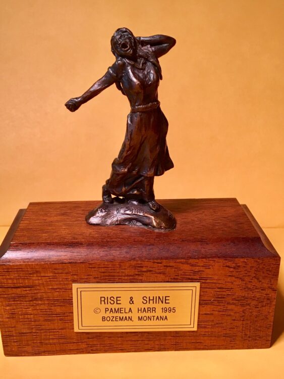 Bronze sculpture of a girl standing up, stretching.